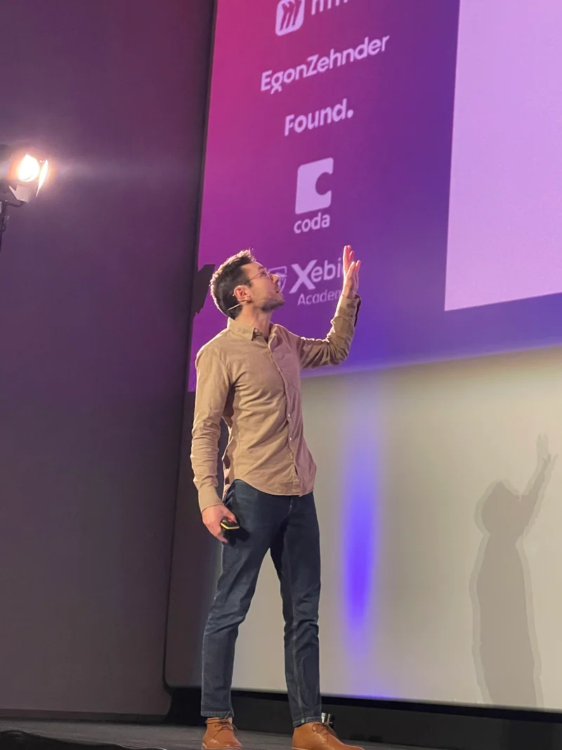Ben Breuner on stage at Product Management Festival, gesturing toward the stage screen.
